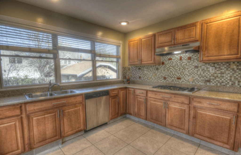 Modern kitchen featuring wooden cabinets, stainless steel appliances, and a countertop with a sink and a window that offers a view of the outdoors.